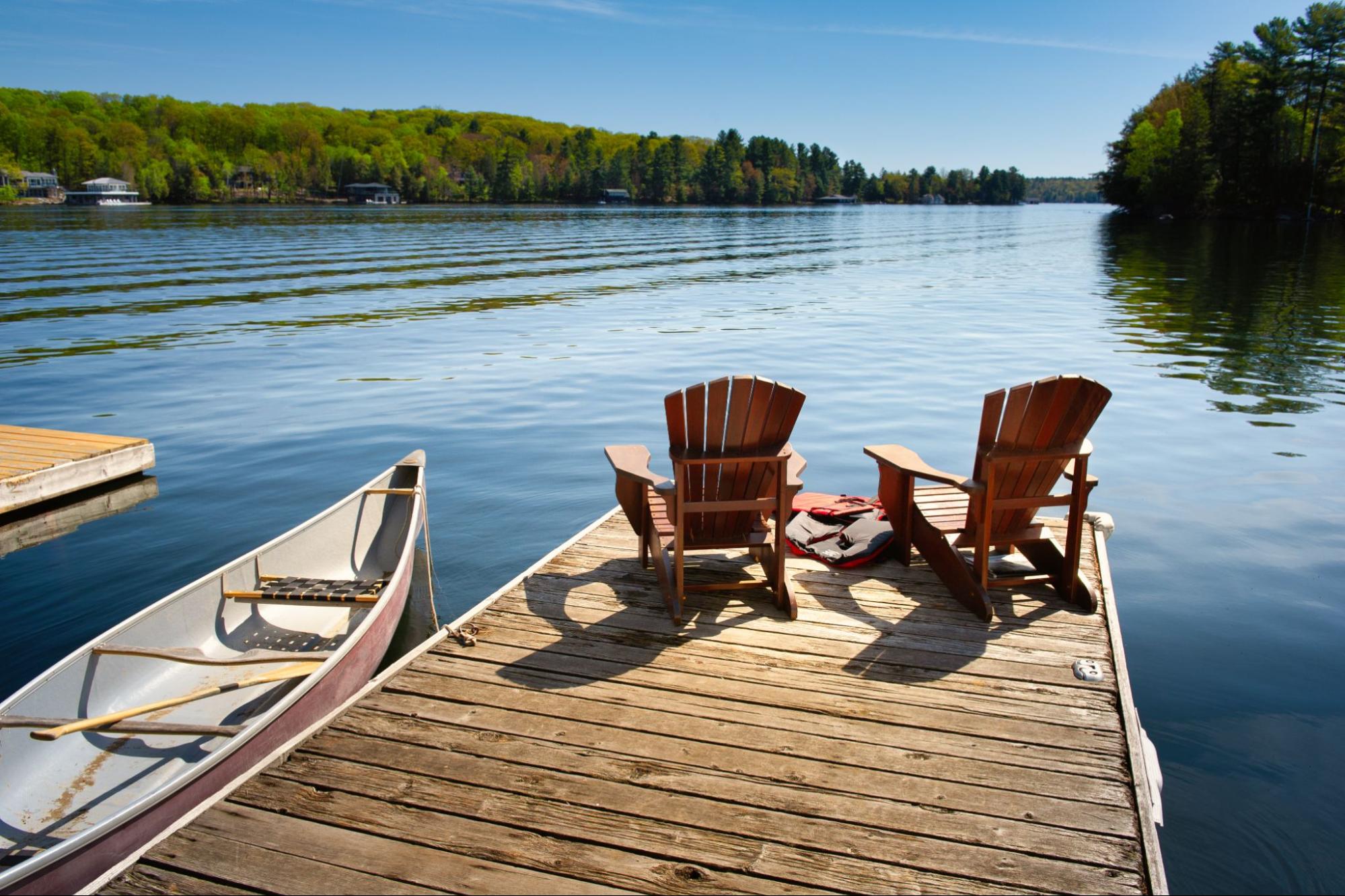 two wood chairs on a dock on a lake ©Alessandro Cancian